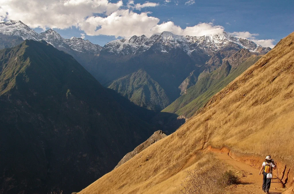 Senderista caminando por la ladera del cañón con montañas nevadas al fondo