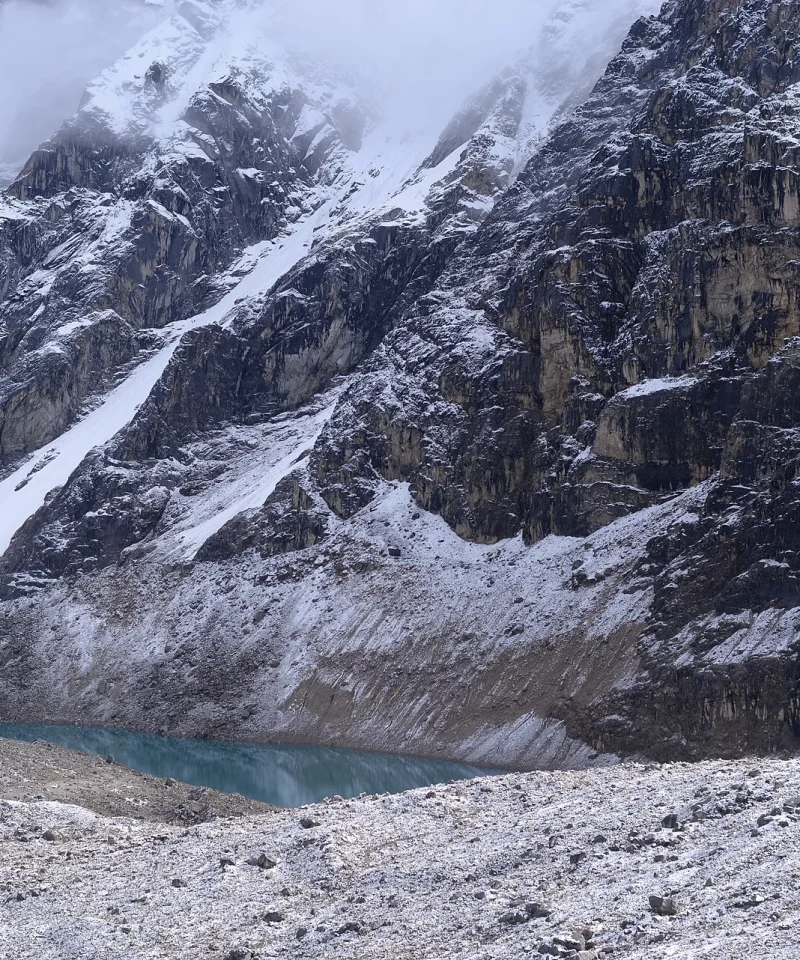 Laguna turquesa al pie de paredes nevadas cerca del paso Inca Chiriaska, en la ruta Salkantay
